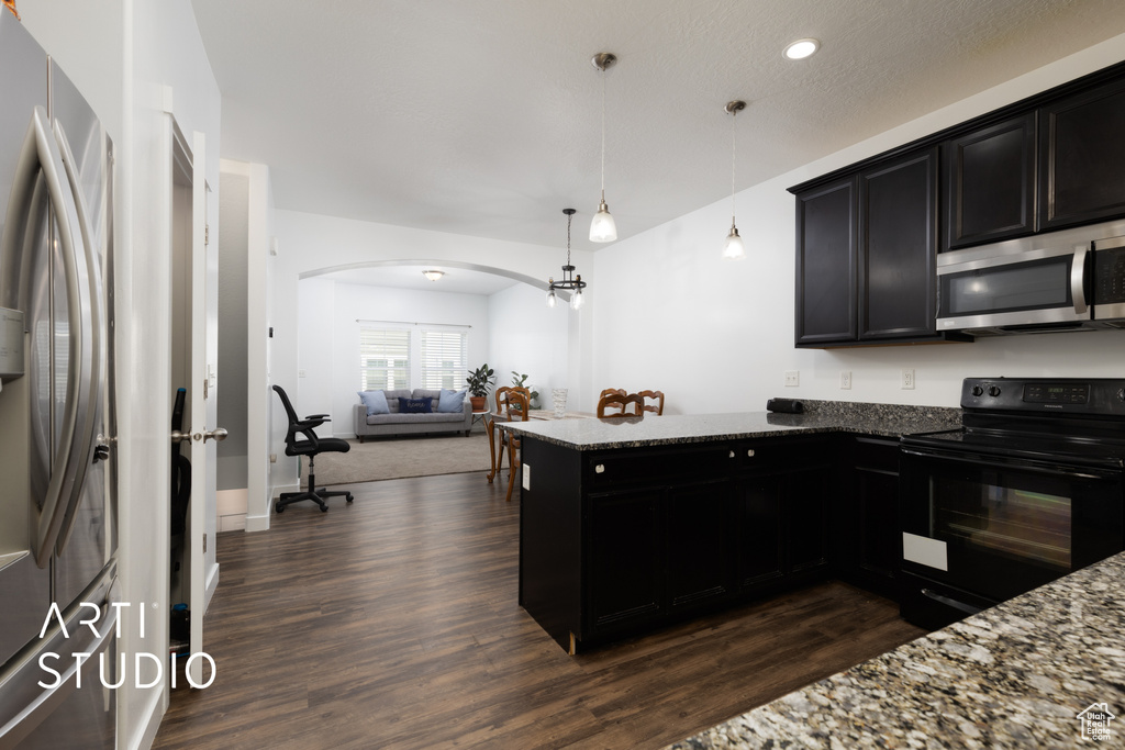 Kitchen featuring stainless steel appliances, arched walkways, dark wood-type flooring, dark cabinetry, and recessed lighting