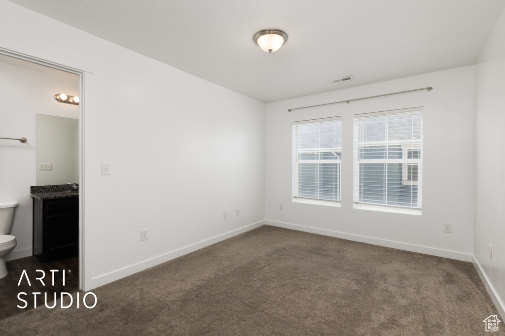 Empty room featuring dark carpet and baseboards