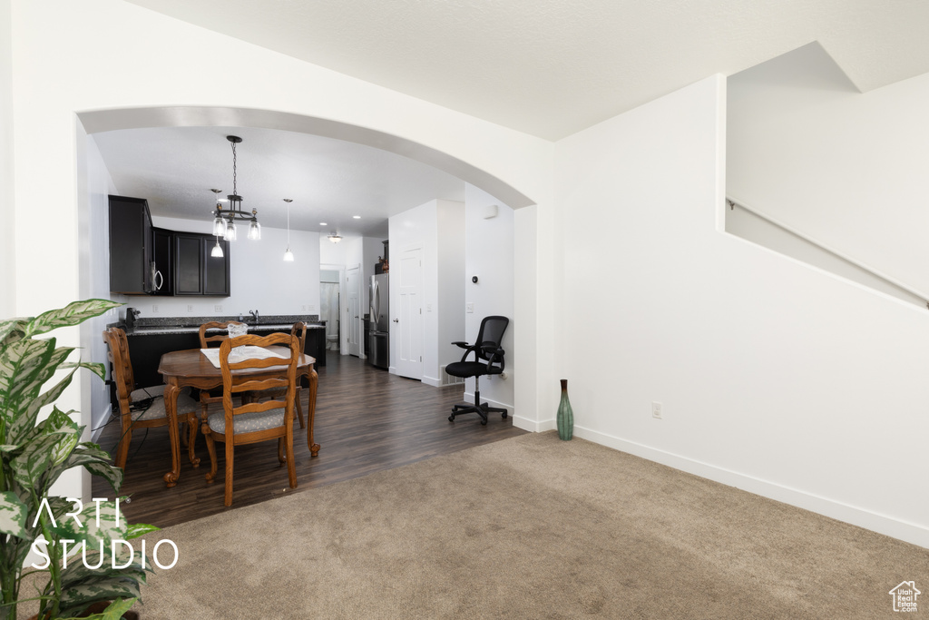 Dining area featuring arched walkways, dark colored carpet, baseboards, and a chandelier