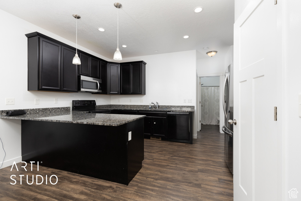 Kitchen with black appliances, a peninsula, dark cabinetry, dark wood-style floors, and recessed lighting