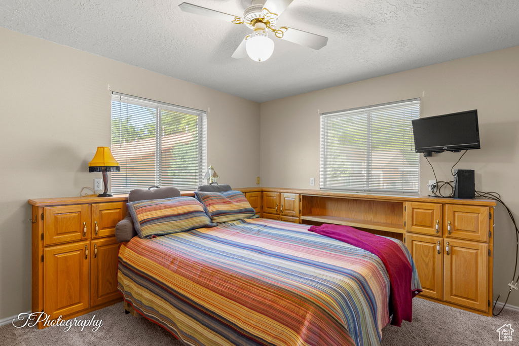 Bedroom with light carpet, a textured ceiling, ceiling fan, and baseboards
