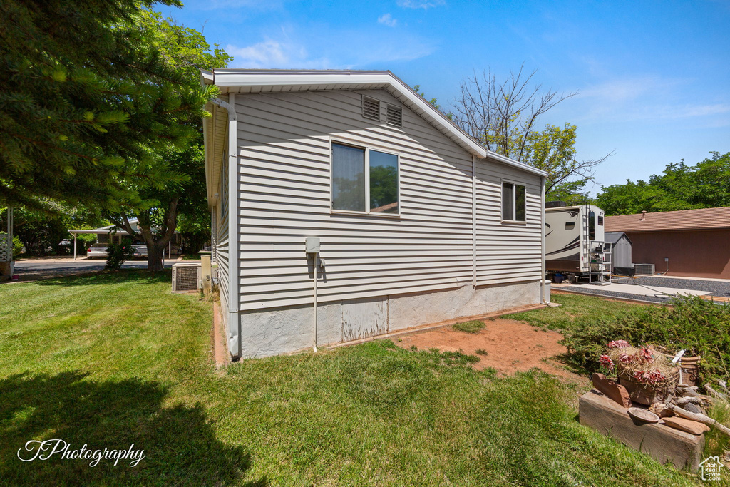View of side of property with a lawn and central air condition unit