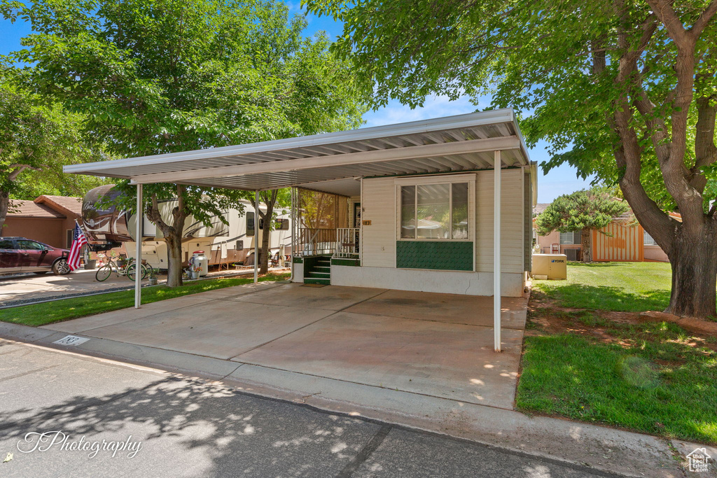 View of front of house with an attached carport and a front lawn