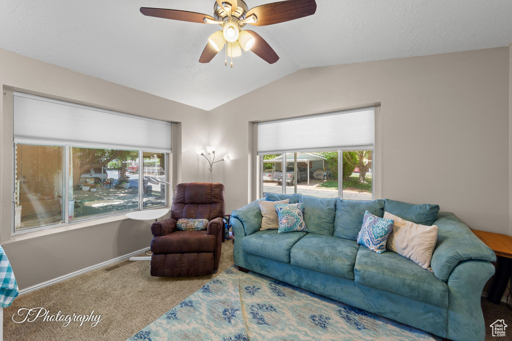 Carpeted living room with vaulted ceiling, ceiling fan, and baseboards