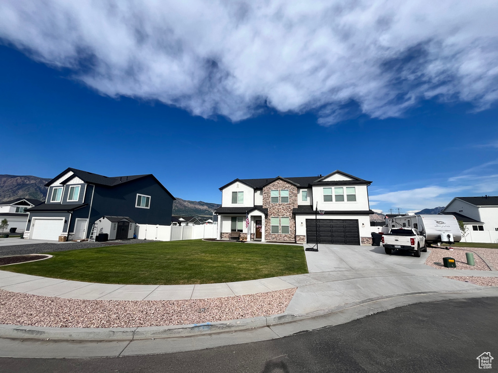 View of front of home featuring an attached garage, stone siding, concrete driveway, and a residential view