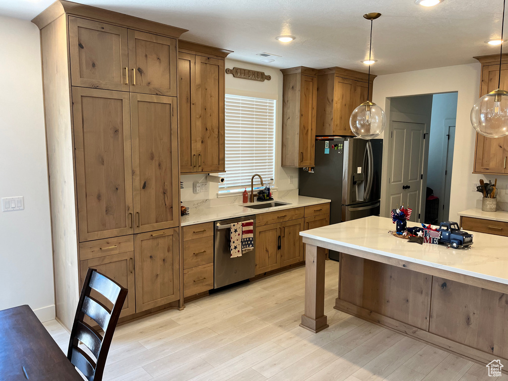 Kitchen featuring stainless steel appliances, a sink, light countertops, pendant lighting, and recessed lighting