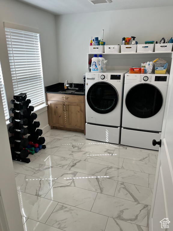 Laundry room with light marble finish floors, washer and clothes dryer, and a sink