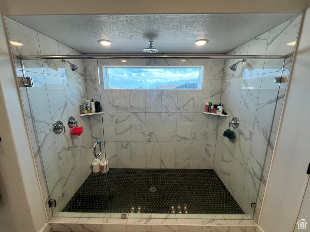 Full bathroom with healthy amount of natural light, a marble finish shower, and a textured ceiling
