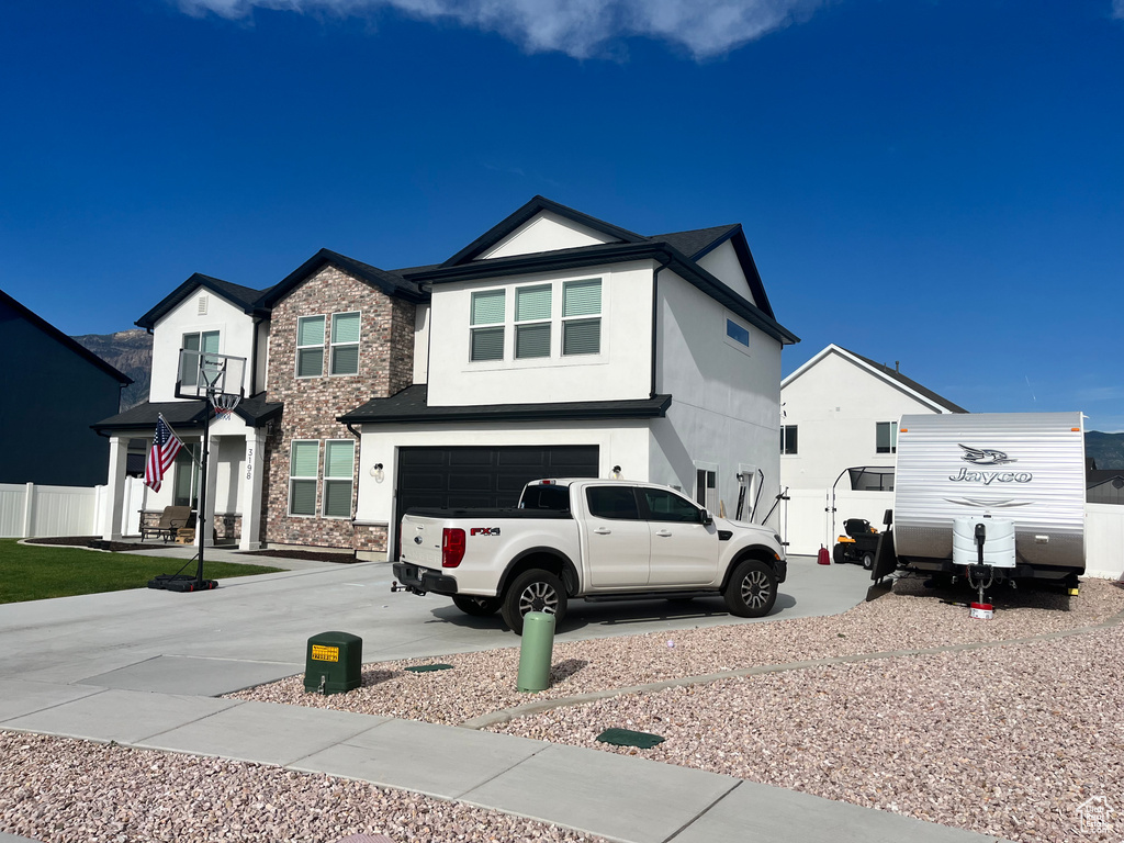 View of front facade with stucco siding, an attached garage, and concrete driveway