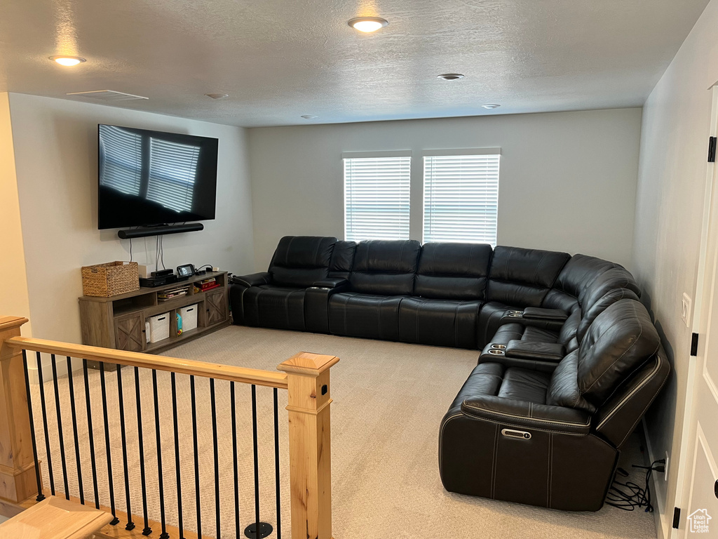 Living area with carpet flooring, a textured ceiling, and recessed lighting