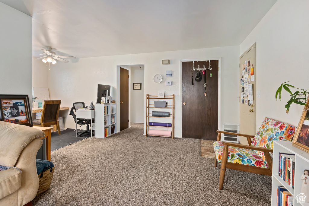 Carpeted living area featuring a ceiling fan