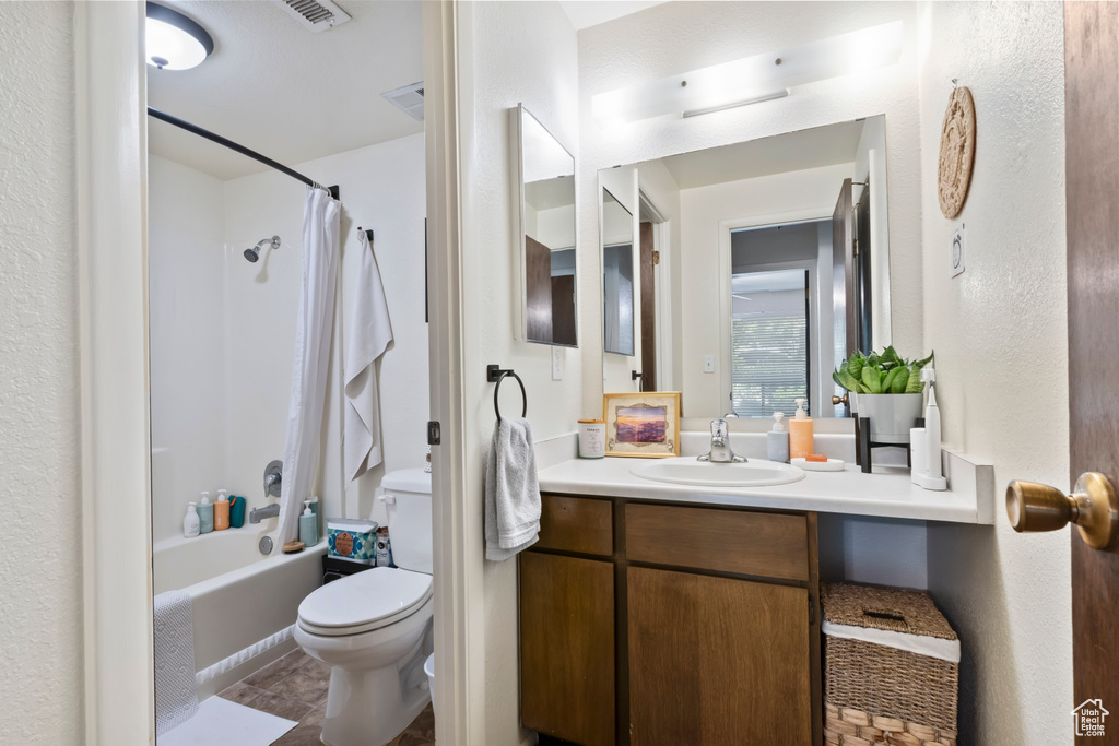 Bathroom with toilet, vanity, shower / bathtub combination with curtain, and tile patterned flooring