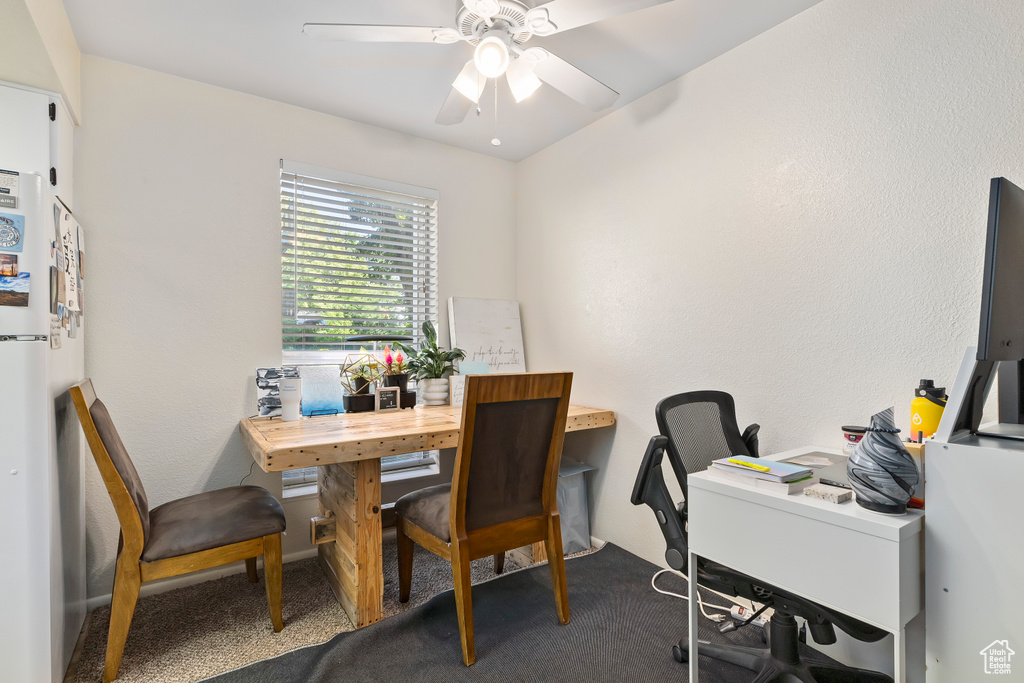Carpeted dining area with ceiling fan and a desk