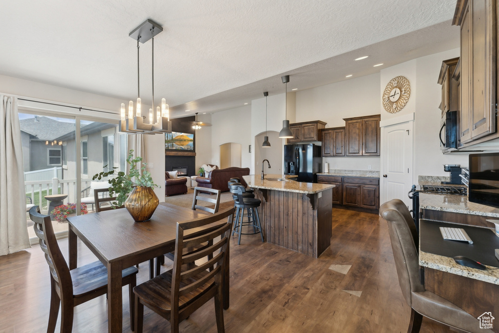 Dining area with arched walkways, dark wood-type flooring, a chandelier, recessed lighting, and a textured ceiling