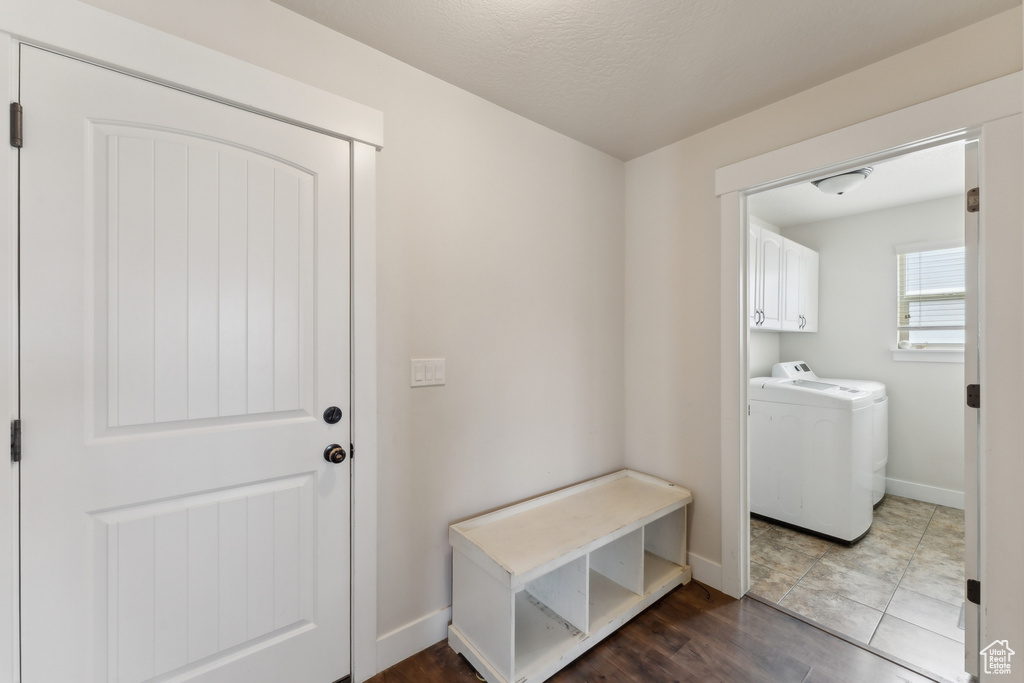 Washroom with cabinet space, baseboards, and washer and clothes dryer