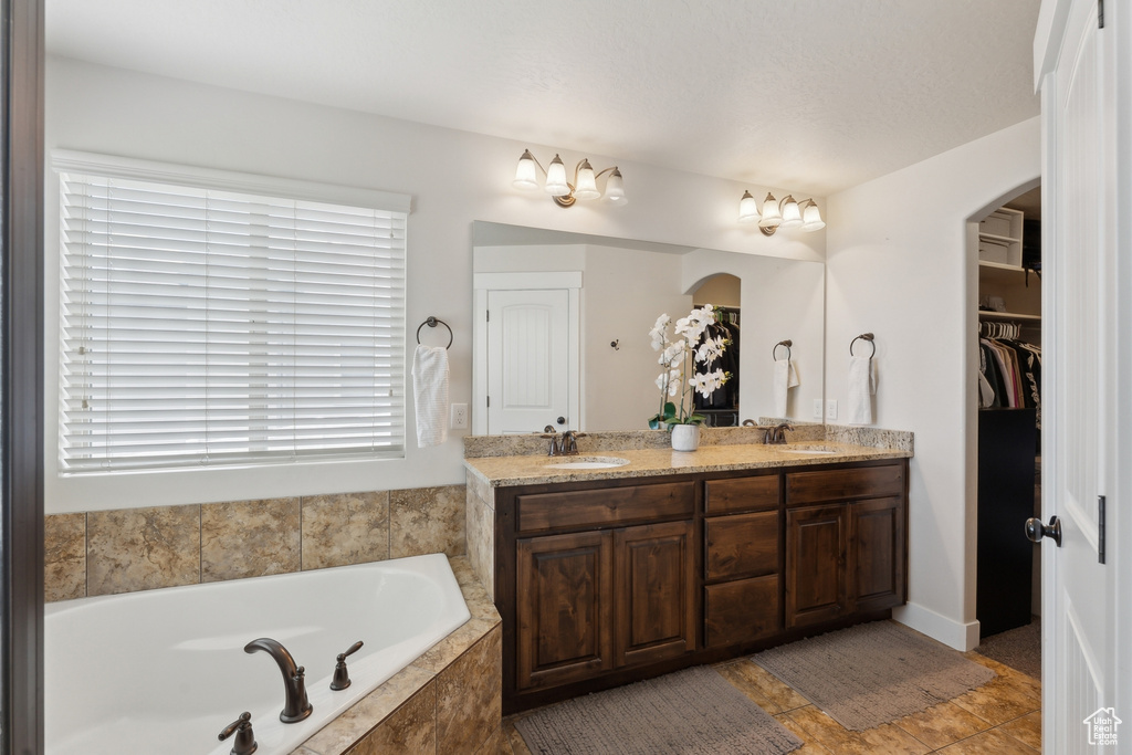 Full bathroom with double vanity, a bath, and a spacious closet
