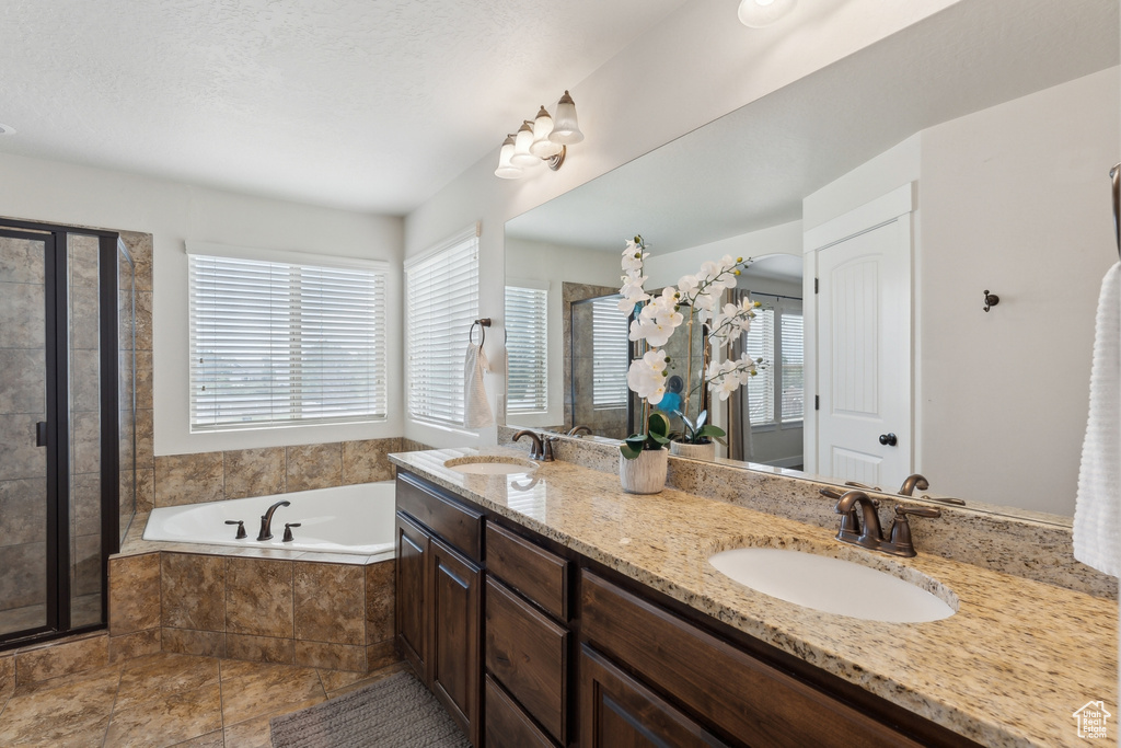 Full bathroom featuring a bath, double vanity, and a stall shower