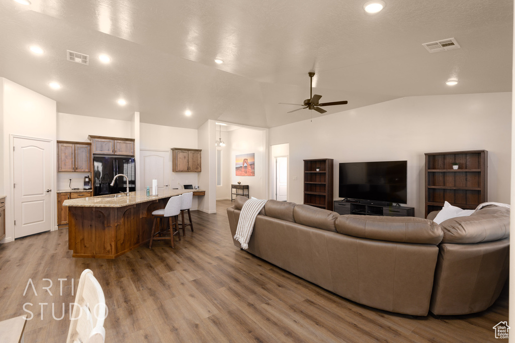 Living room featuring vaulted ceiling, a ceiling fan, and wood finished floors