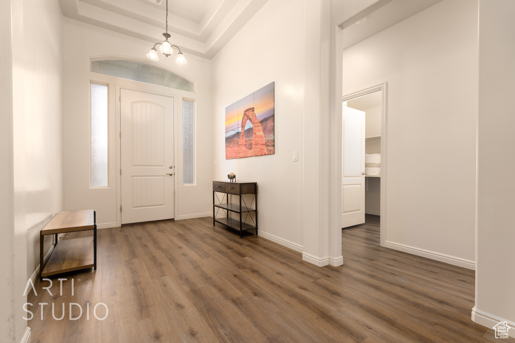 Foyer entrance featuring dark wood finished floors, a chandelier, baseboards, and a raised ceiling