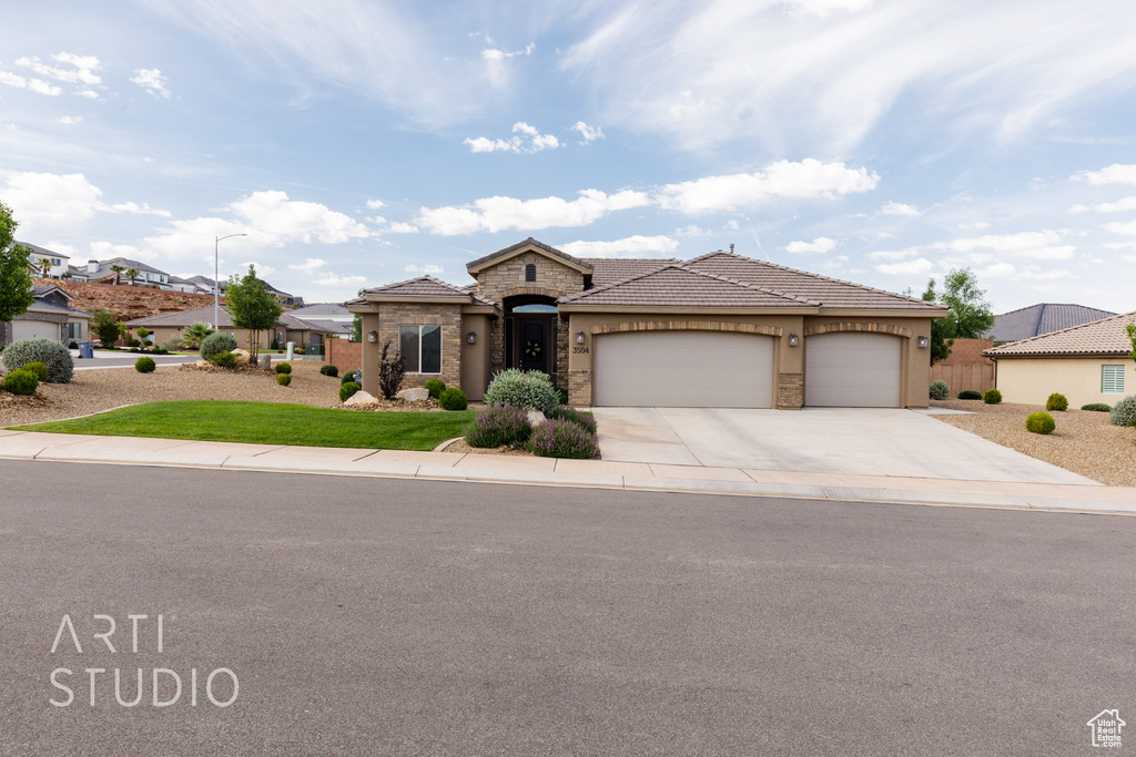 View of front of property featuring driveway, stone siding, an attached garage, a tile roof, and stucco siding