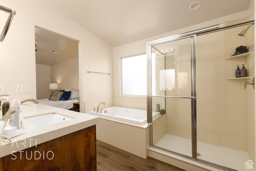 Bathroom featuring wood finished floors, vanity, a bath, and a shower stall