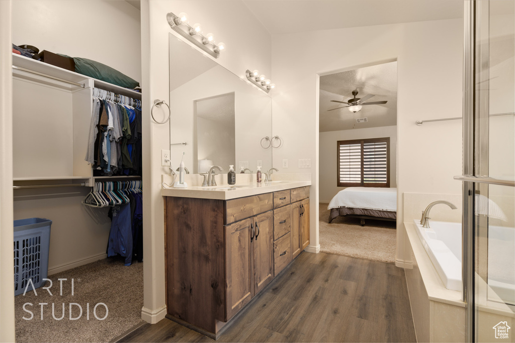Bathroom featuring a ceiling fan, wood finished floors, double vanity, and baseboards