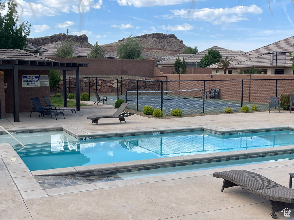 Community pool featuring a mountain view, a tennis court, and a patio