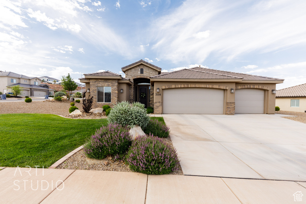 View of front facade featuring concrete driveway, a front lawn, an attached garage, stucco siding, and a tile roof