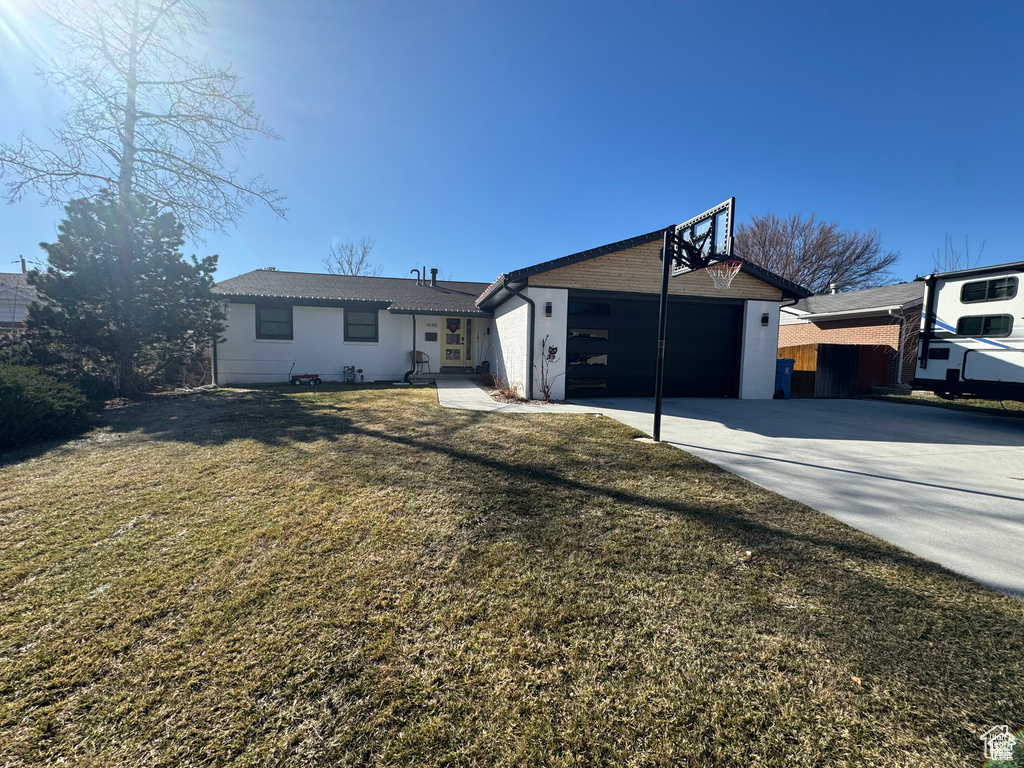 Rear view of property with concrete driveway, a lawn, and an attached garage