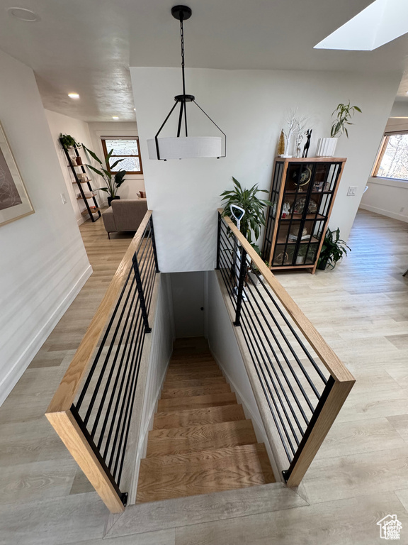 Staircase featuring a skylight, wood finished floors, baseboards, and recessed lighting