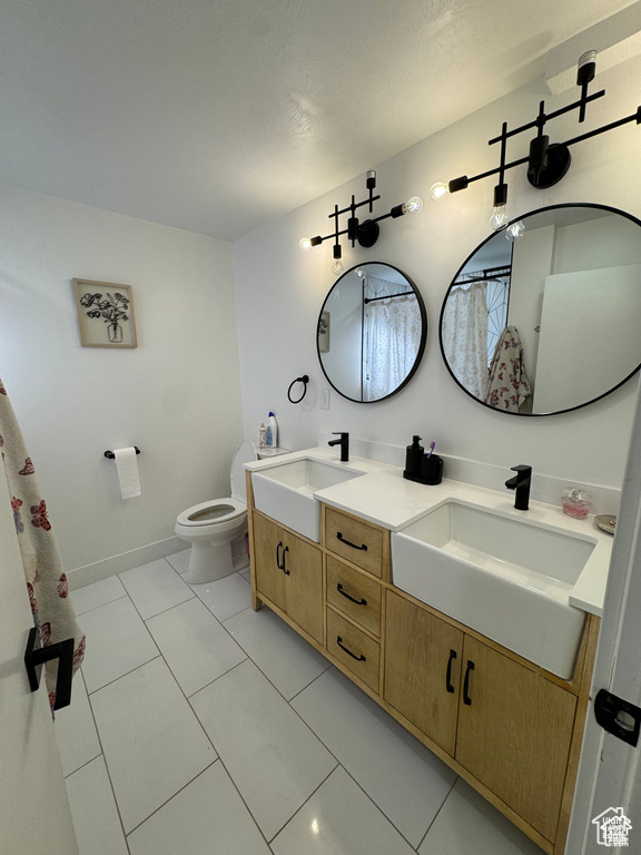 Bathroom with double vanity, toilet, and tile patterned floors
