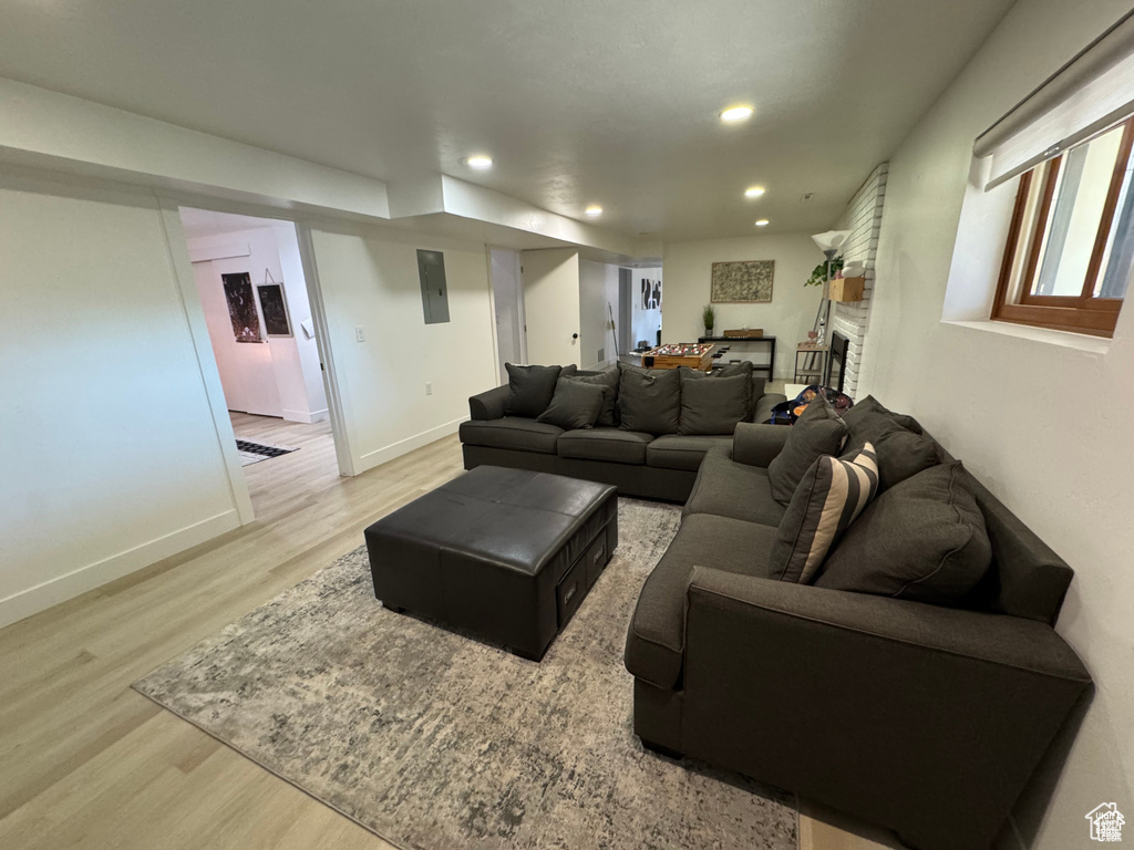 Living room with light wood finished floors, recessed lighting, baseboards, and a fireplace