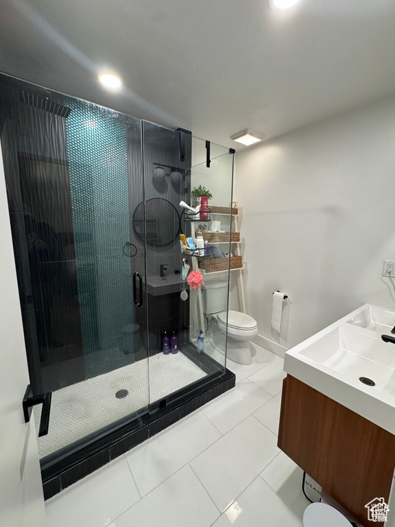 Bathroom featuring toilet, vanity, a shower stall, and tile patterned flooring