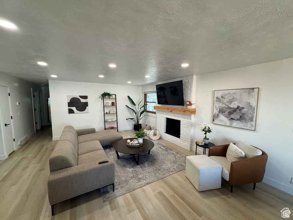 Living area featuring wood finished floors, recessed lighting, a textured ceiling, baseboards, and a fireplace