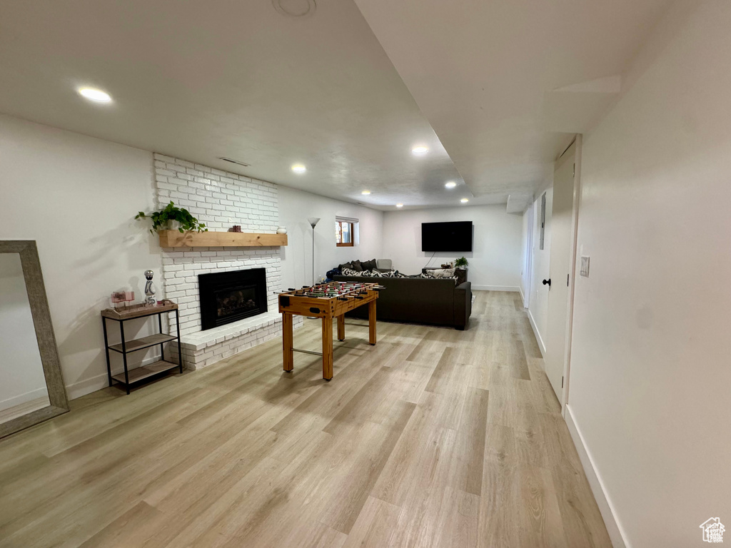 Living area featuring a brick fireplace, light wood finished floors, baseboards, and recessed lighting