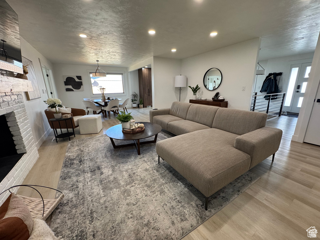 Living area with light wood-type flooring, a brick fireplace, recessed lighting, and baseboards