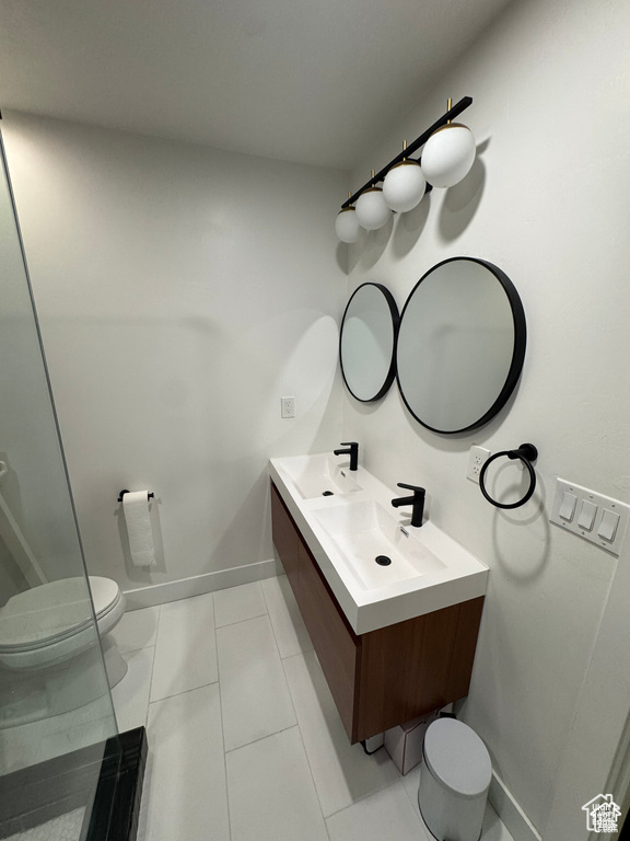 Bathroom with toilet, double vanity, and baseboards