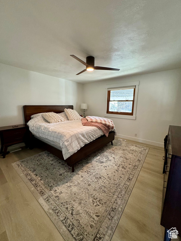 Bedroom with light wood-style flooring, ceiling fan, and baseboards