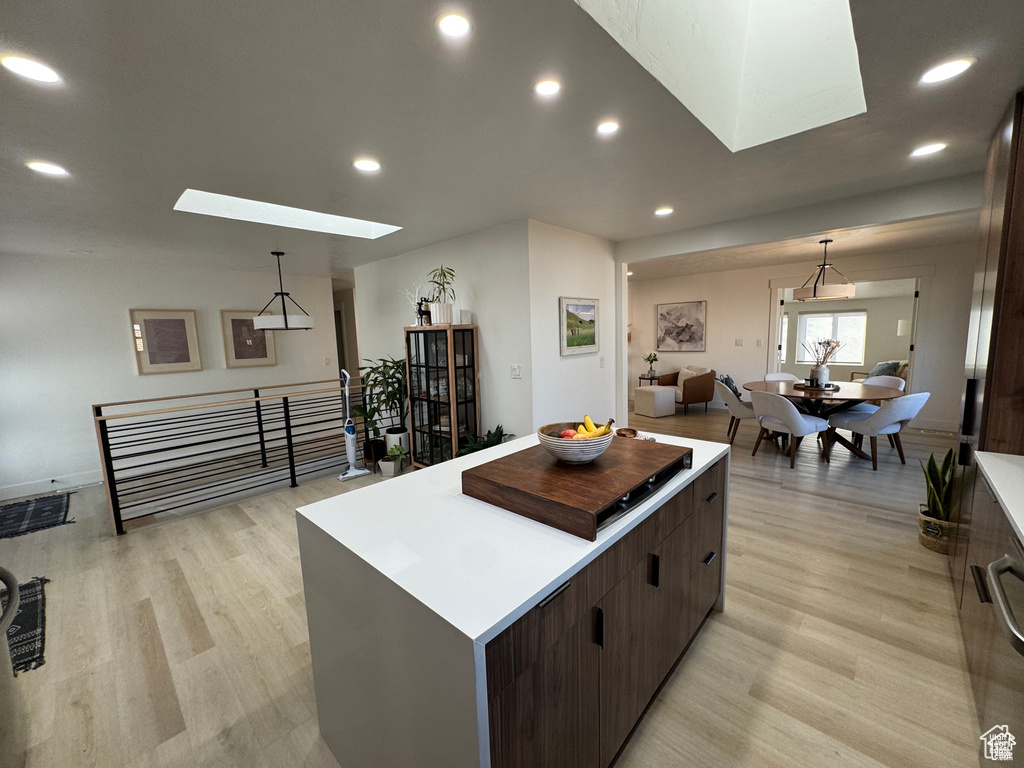 Kitchen with a skylight, a kitchen island, light wood-type flooring, recessed lighting, and decorative light fixtures