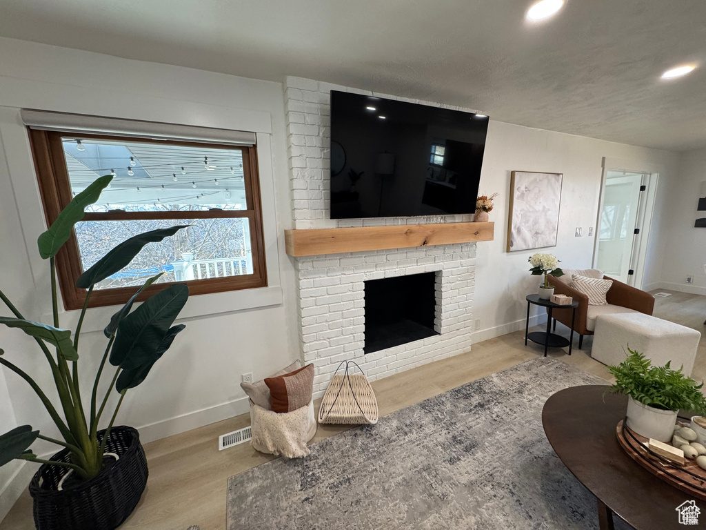 Living area featuring wood finished floors, baseboards, recessed lighting, and a brick fireplace