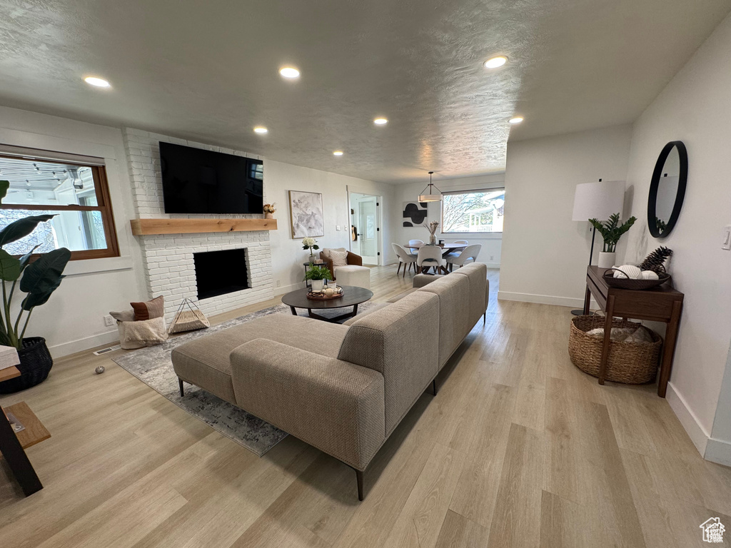 Living area with light wood finished floors, baseboards, recessed lighting, and a fireplace