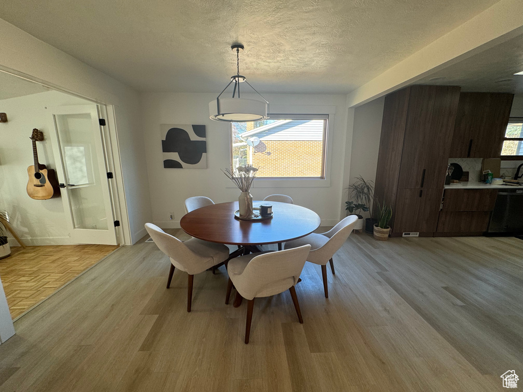 Dining room with light wood-type flooring, a textured ceiling, and baseboards
