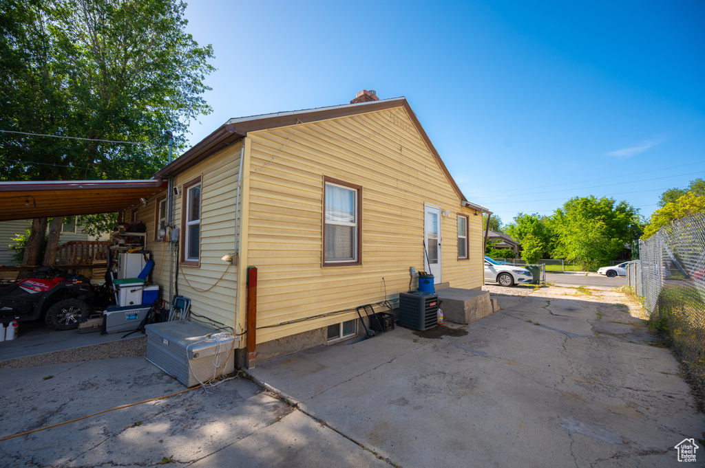 View of side of home with a chimney and central AC unit