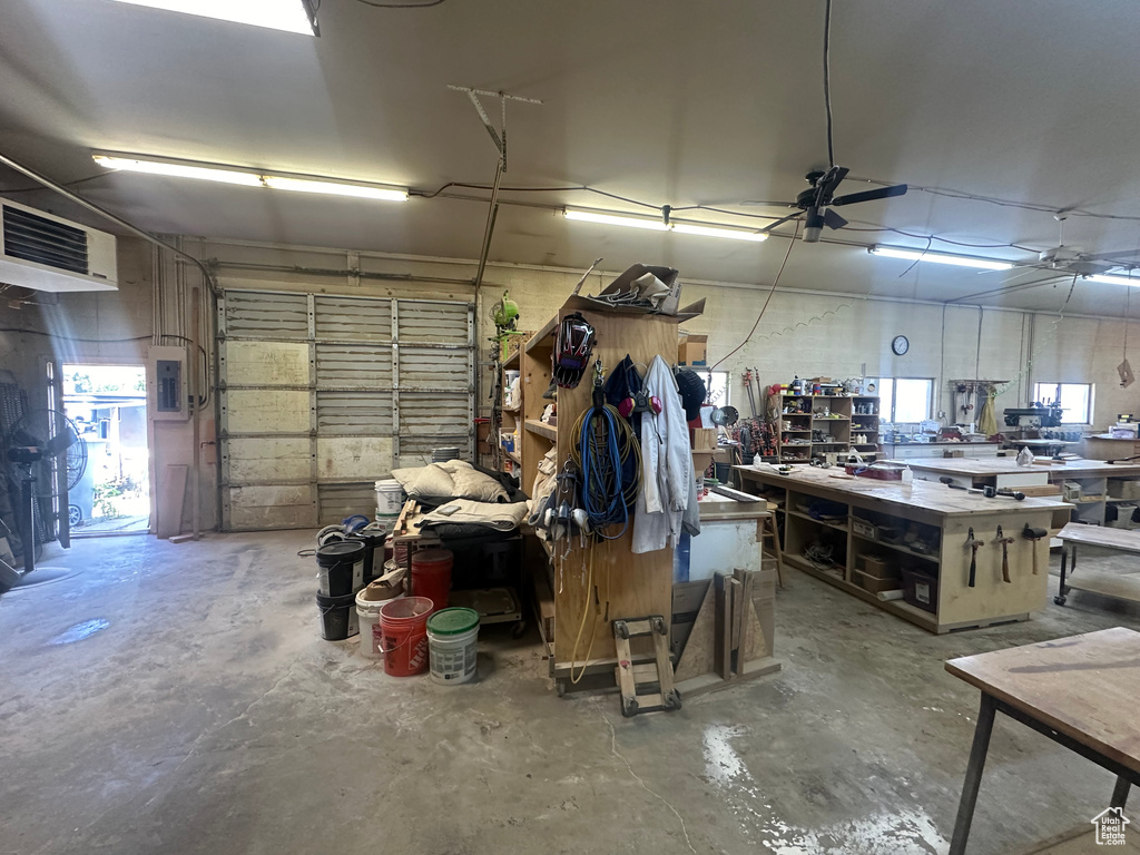 Garage featuring a heating unit, electric panel, and a workshop area