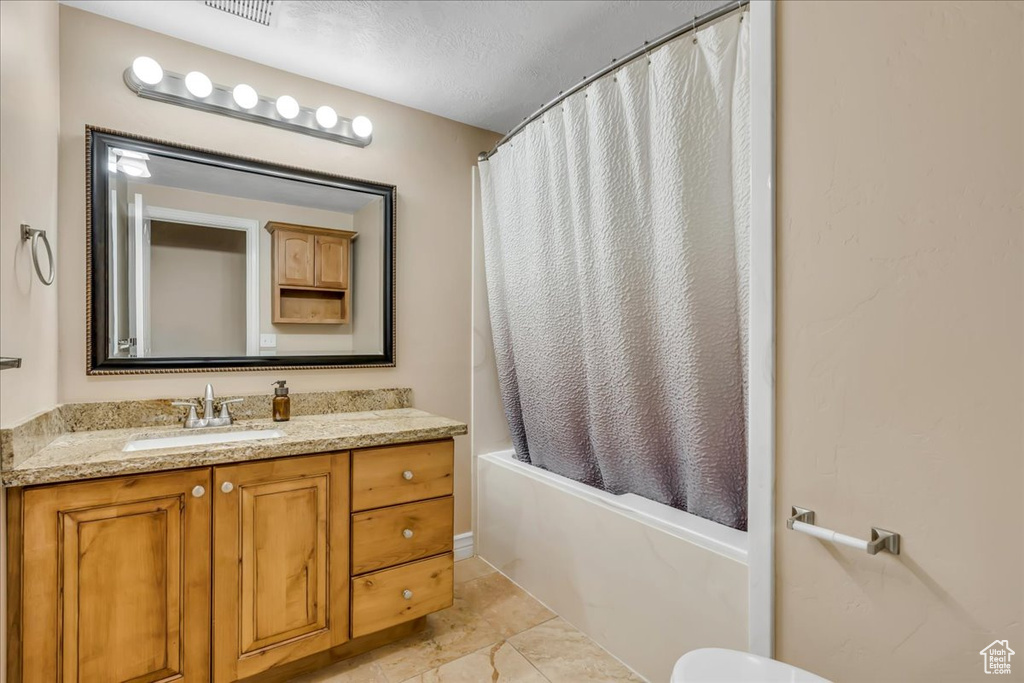 Bathroom with vanity, shower / bathtub combination with curtain, and toilet