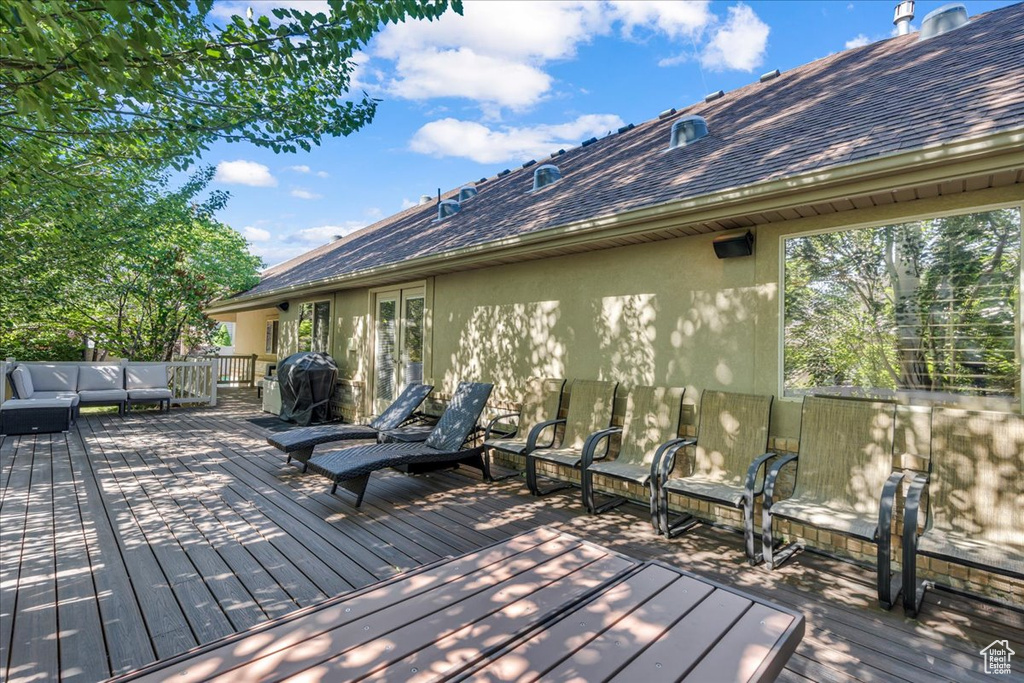 Wooden deck featuring an outdoor living space and a grill