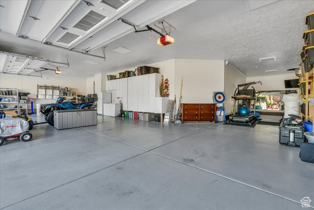 Garage featuring a garage door opener and freestanding refrigerator