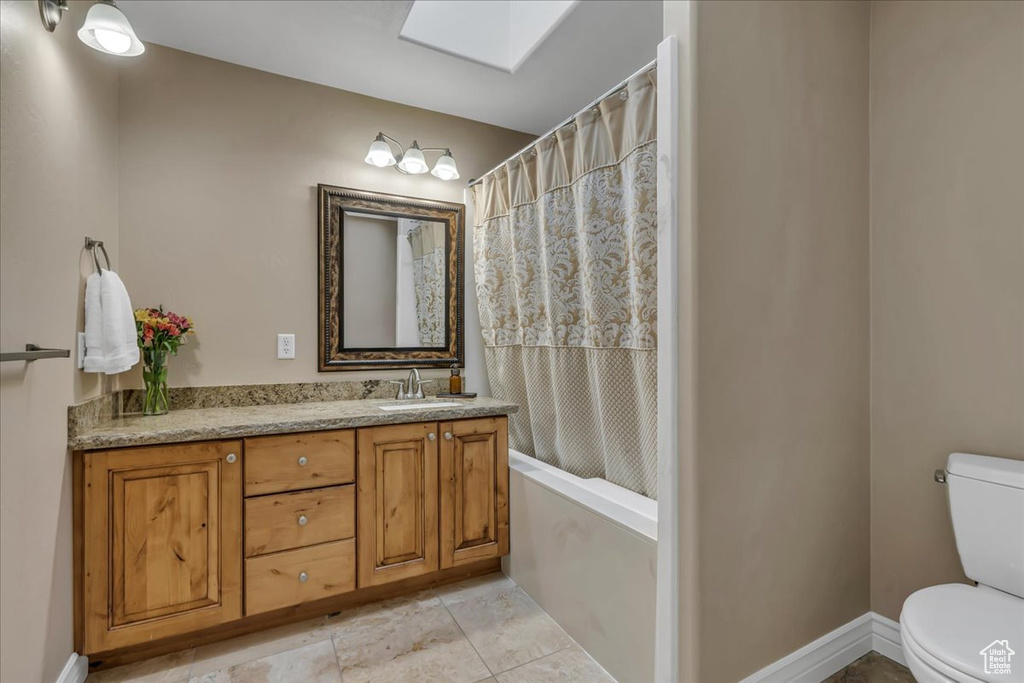 Bathroom with toilet, vanity, and tile patterned floors