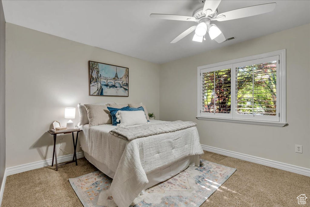 Bedroom with light colored carpet, baseboards, and ceiling fan