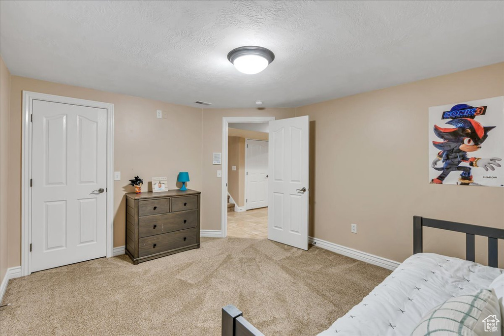 Carpeted bedroom featuring baseboards and a textured ceiling
